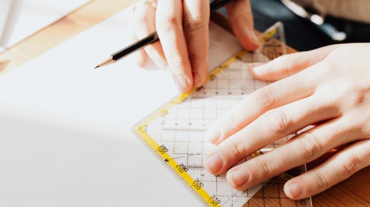 hands holding a ruler and pencil